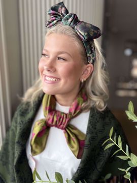 Hårbøyle med stor, flyttbar og avtagbar sløyfe. Bredde ca. 6 cm. Grønntoner med lilla, blomsterinspirert mønster. 